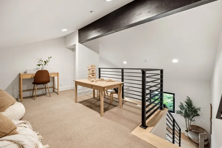 Carpeted loft area with recessed lighting, exposed wood beam, and black horizontal bar railing