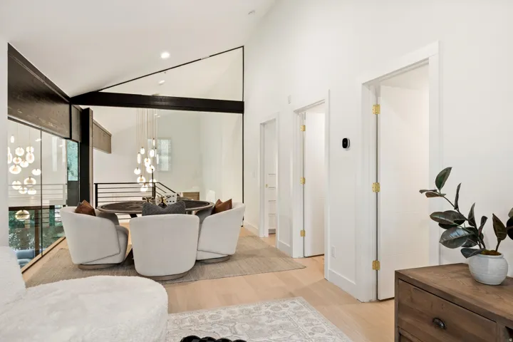 Vaulted ceilings, exposed beams, and a multi-level design featuring a suspended lighting fixture
