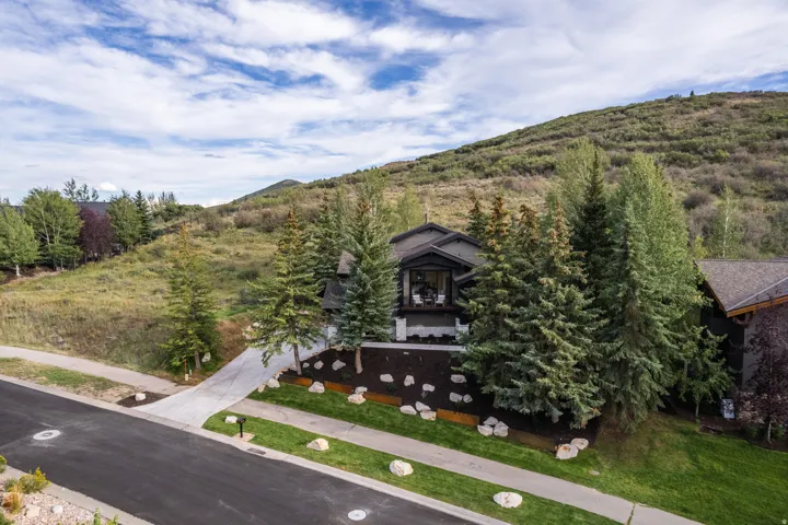 Modern exterior with a stone accent wall, private balcony, and mature evergreen landscaping