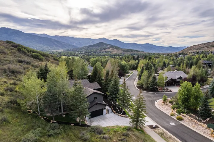 Mountainous terrain, surrounding green foliage, paved cul-de-sac, asphalt driveway, and multi-level residences