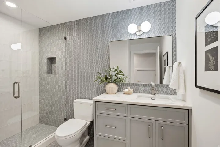 Glass-enclosed shower with a recessed niche, vanity with a white countertop, undermount sink, and a tiled accent wall