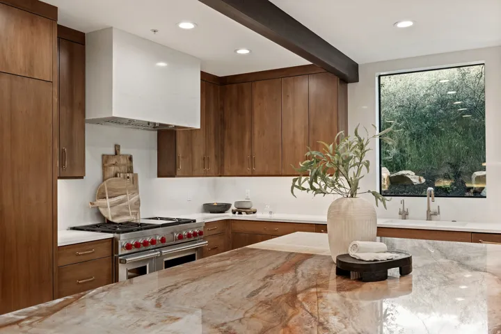 Gourmet kitchen with wood-finish cabinetry, a large kitchen island, stainless steel range with a white range hood, and a built-in sink