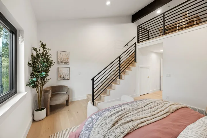 High ceilings with recessed lighting, wood-finish flooring, a contemporary staircase with black metal railings, and a window with black trim