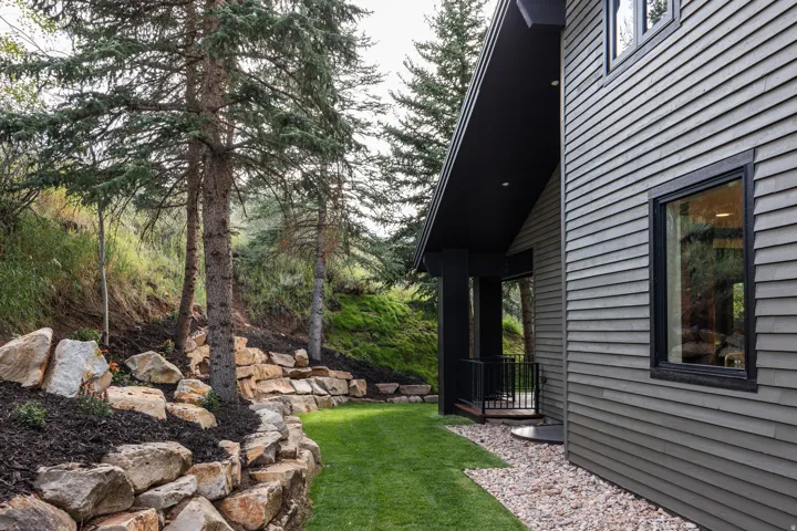 Exterior featuring horizontal siding, black trim windows, a covered porch with dark posts, and a gravel walkway