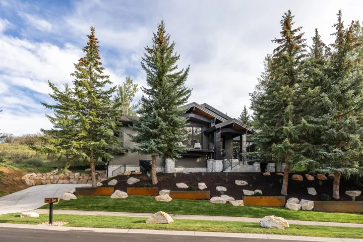 Modern architectural style with dark siding and stone accents