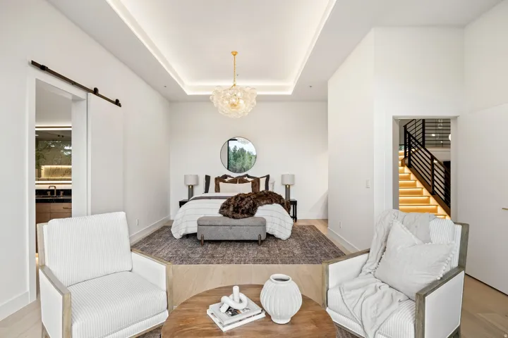 Elevated sleeping area with tray ceiling, contemporary chandelier, and integrated lighting