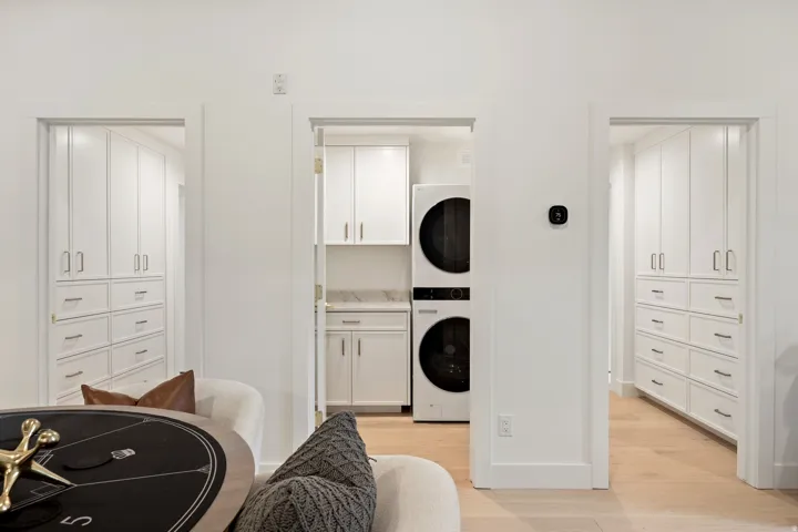 Integrated laundry area with stacked appliances, white cabinetry, and a countertop