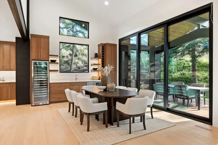 Vaulted ceiling with an exposed beam, light wood-finish flooring, full-height sliding glass doors, built-in wine cooler, and recessed lighting
