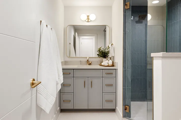 Vanity with light-toned countertop, integrated sink, and gold-tone hardware