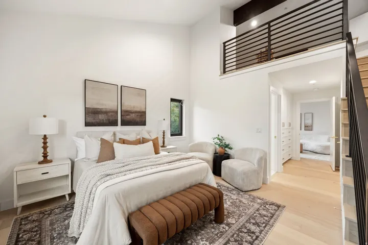 High ceilings, light wood-finish flooring, and a modern black metal railing