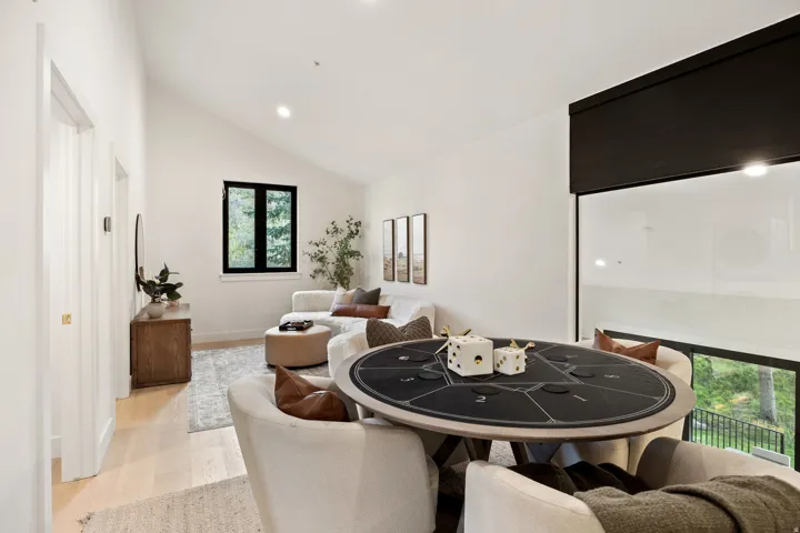 Vaulted ceiling, recessed lighting, wood-finish flooring, black-framed windows, built-in window shade