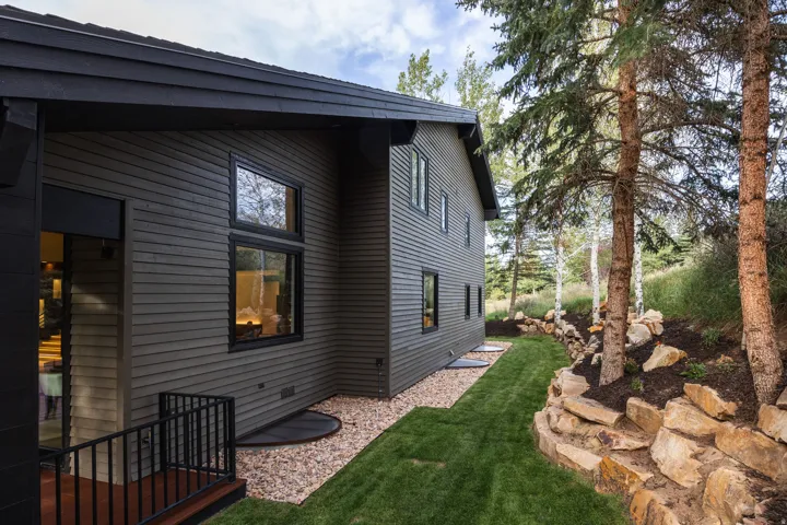 Multi-level exterior with horizontal siding, dark window frames, and a gravel perimeter
