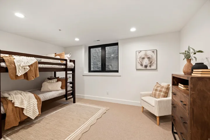 Recessed lighting, neutral carpeting, and a window with black trim