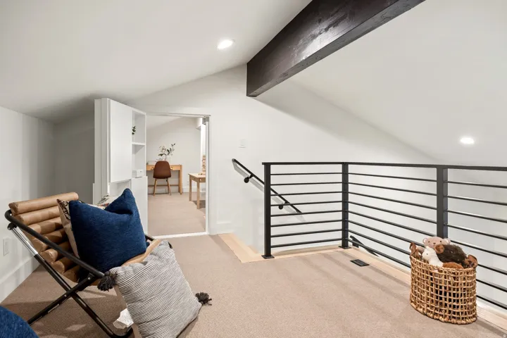 Loft area featuring a vaulted ceiling with exposed wood beam, recessed lighting, carpeted flooring, and a contemporary metal railing