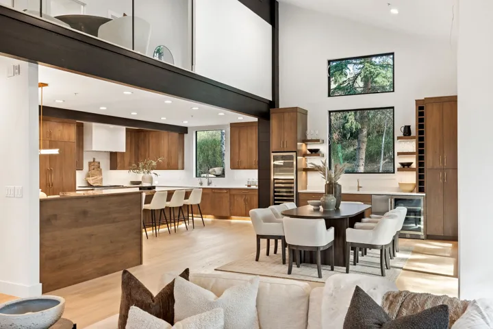 Open-concept living space with vaulted ceilings, a kitchen island with seating, built-in cabinetry, and a wet bar with integrated appliances