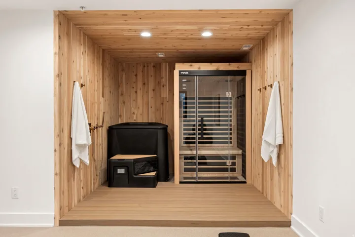 Wood-paneled alcove with recessed lighting, an elevated wood-finish floor, and wall-mounted brass hooks