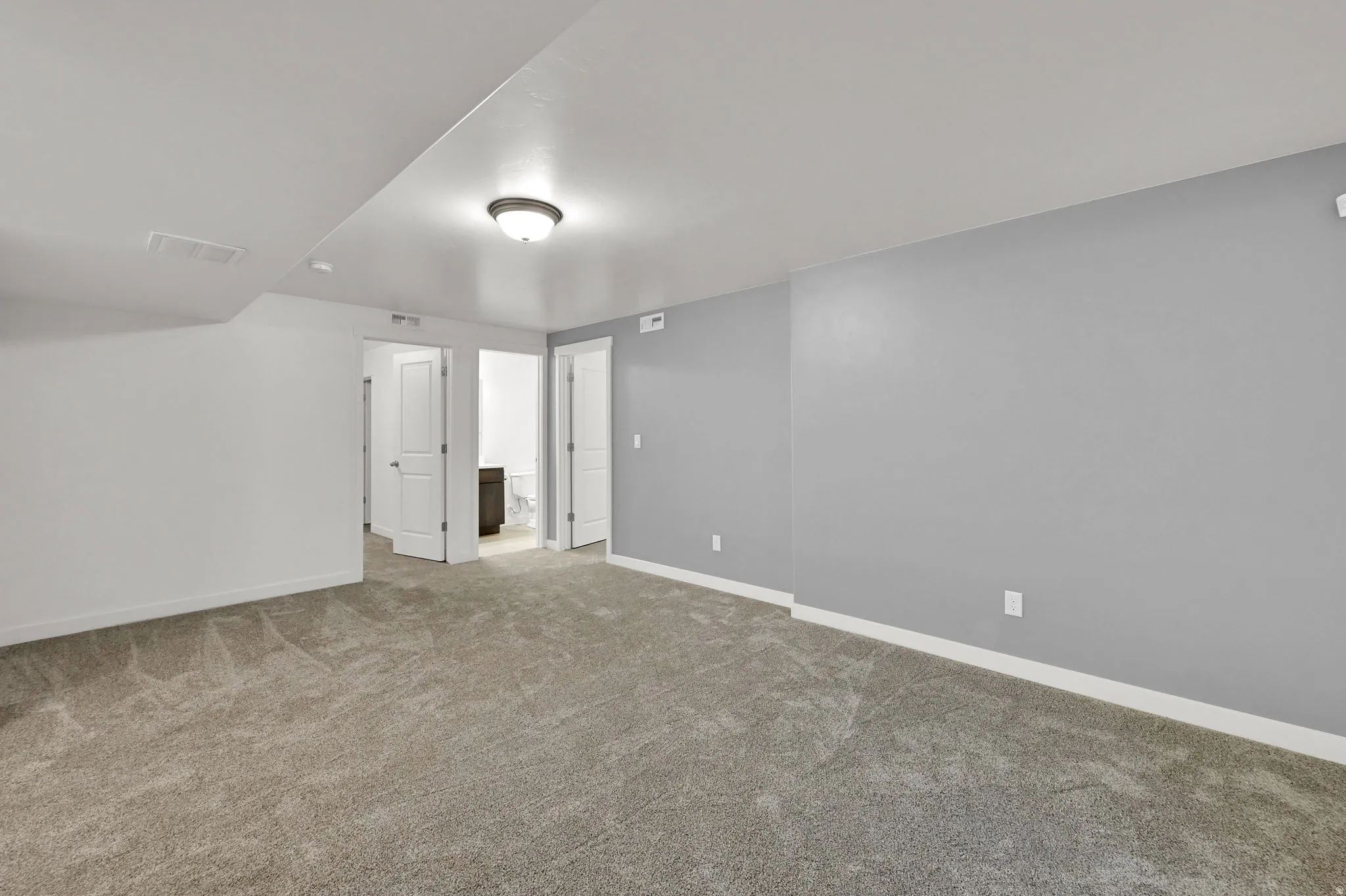 Plush carpet flooring, neutral gray wall paint, flush mount ceiling light fixture, and white trim