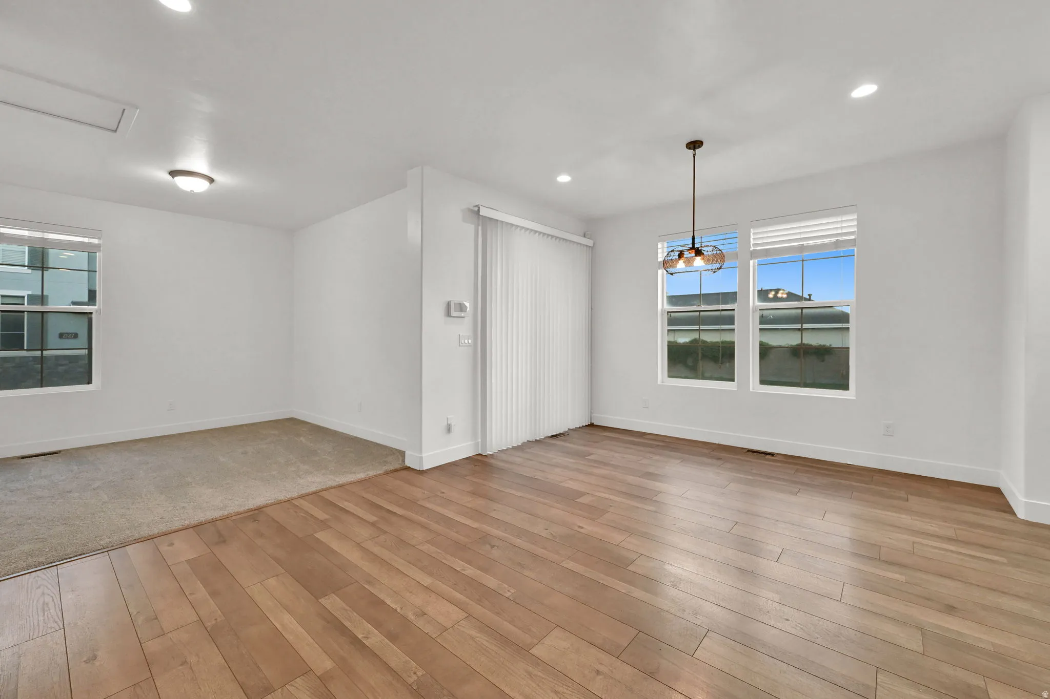 Wood-finish flooring, recessed lighting, and large windows with blinds