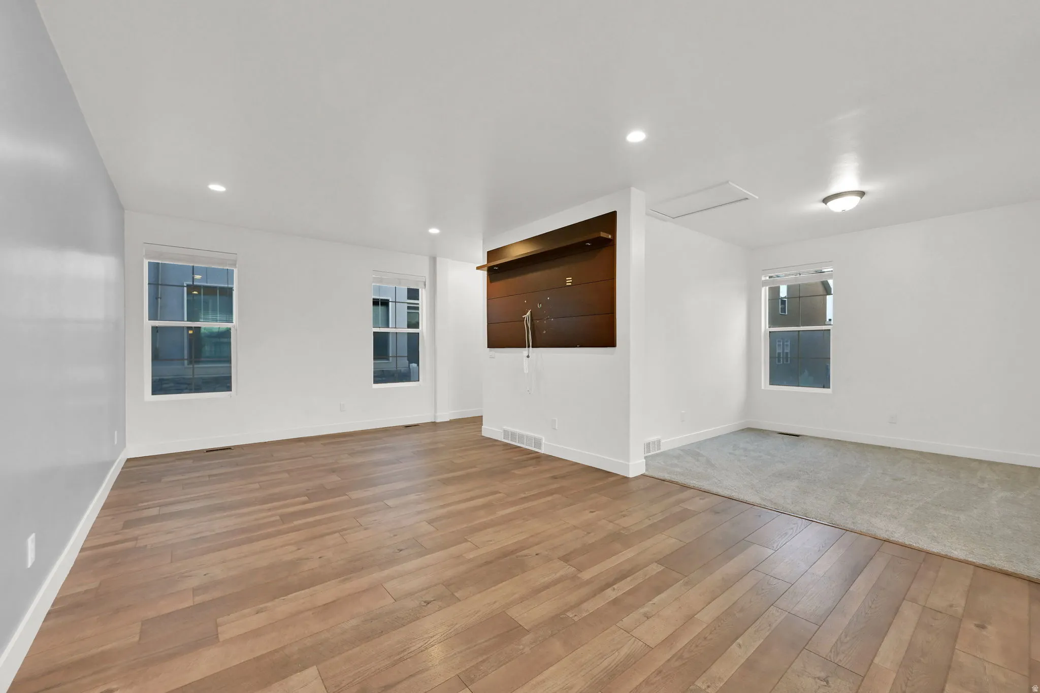 Wood-finish flooring, recessed lighting, built-in shelving, white walls, and carpeted area
