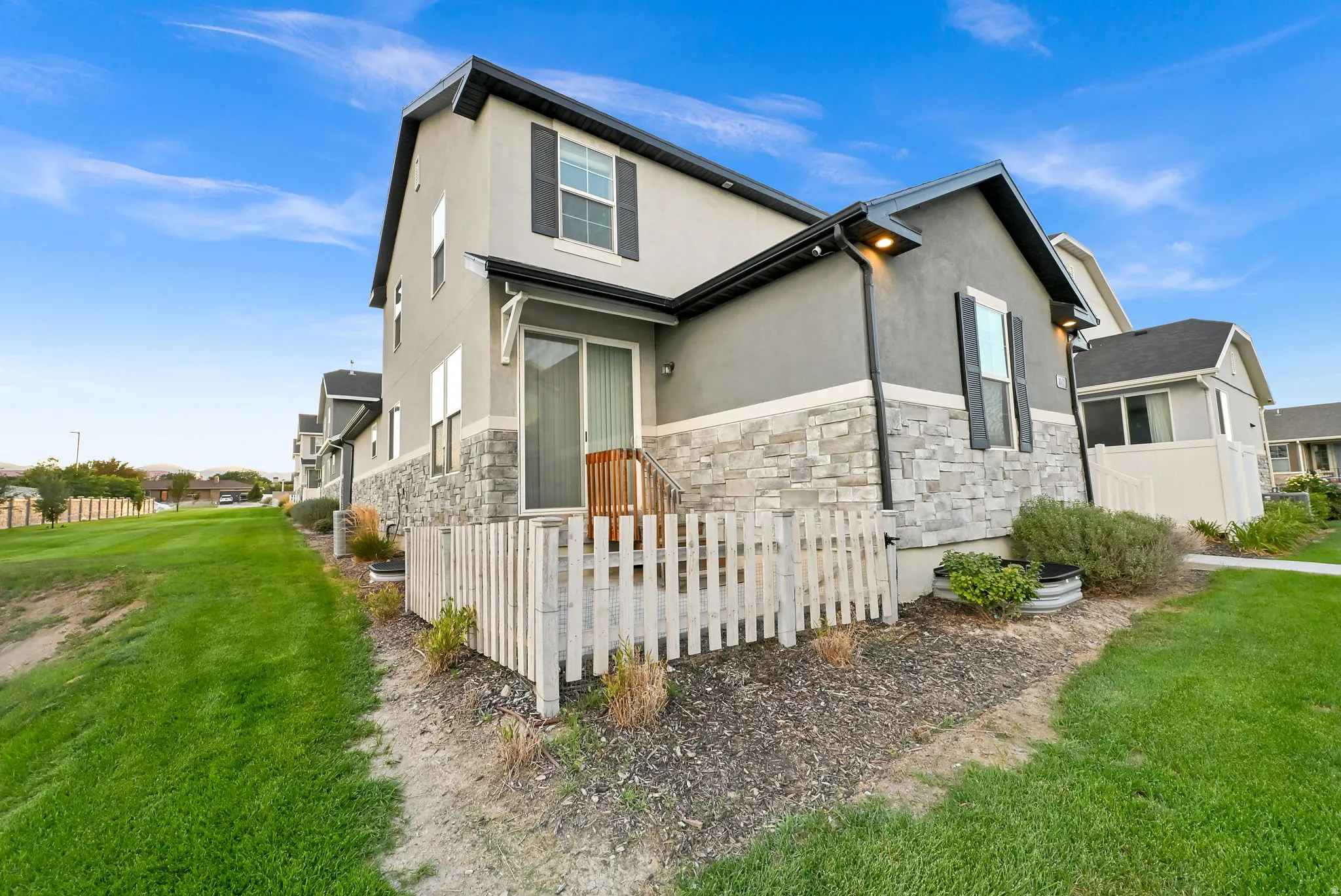 Two-story exterior with a stone and stucco facade, a private deck, and a sliding glass door