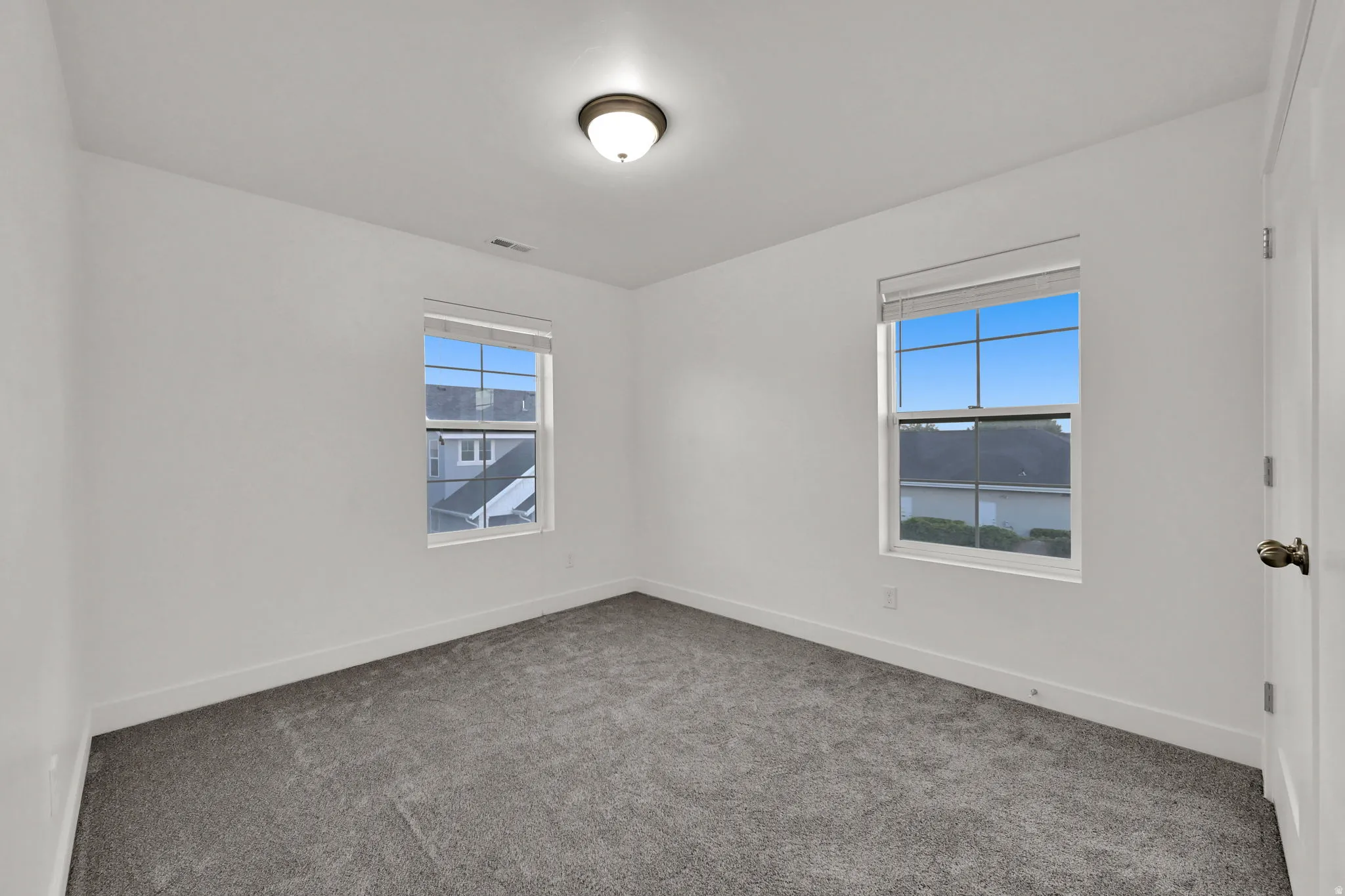 Neutral wall finishes, recessed ceiling light, carpeted flooring, and two double-hung windows