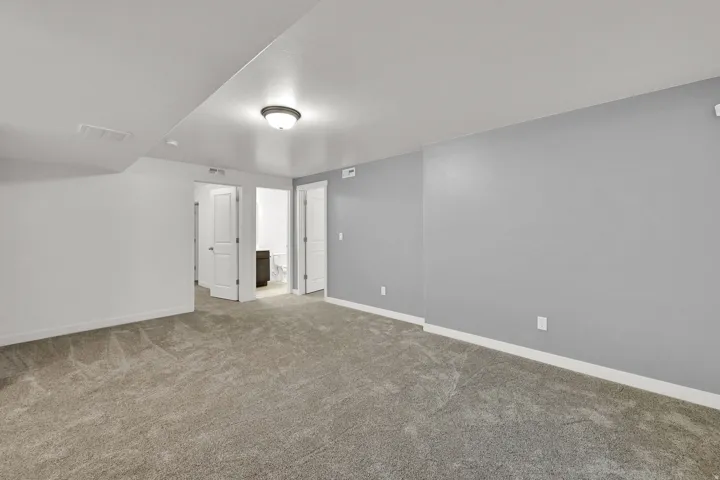 Plush carpet flooring, neutral gray wall paint, flush mount ceiling light fixture, and white trim