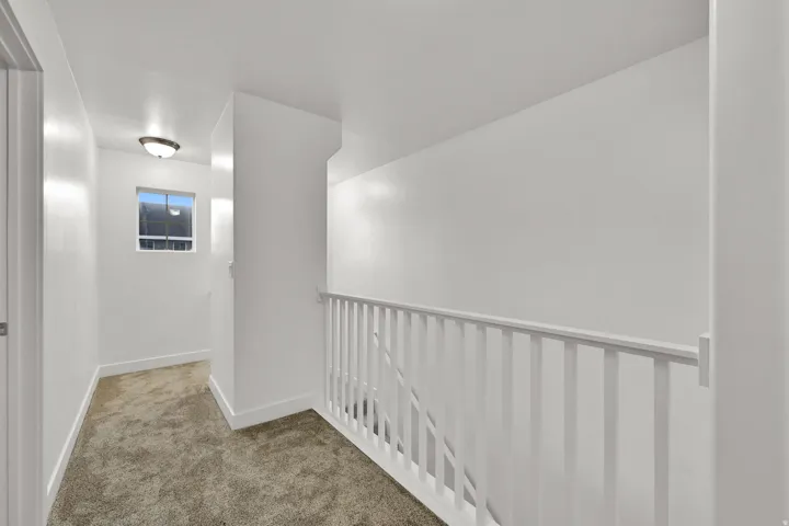 White painted walls, carpeted flooring, window with natural light, and a flush-mount ceiling light fixture