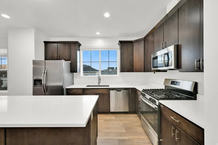 Kitchen featuring dark wood-finish cabinetry, white countertops, and stainless steel appliances