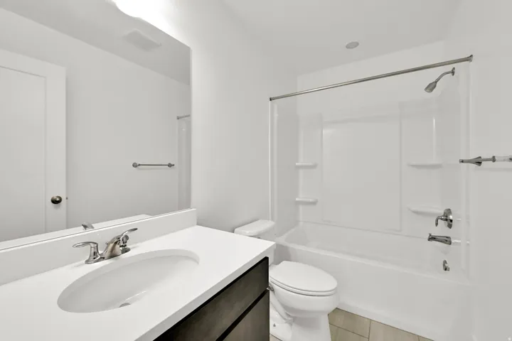 Bathroom featuring a white vanity with an undermount sink, chrome fixtures, a full-width mirror, and a shower/tub combination with a white surround