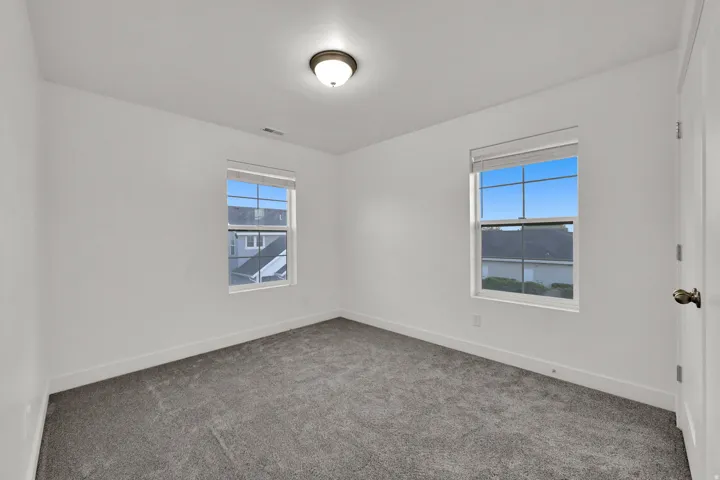 Neutral wall finishes, recessed ceiling light, carpeted flooring, and two double-hung windows