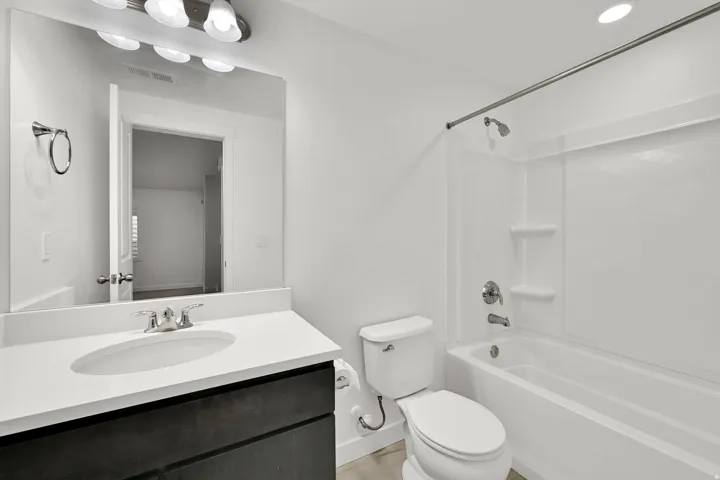 Modern vanity with a white countertop and integrated sink, chrome faucet, and expansive wall mirror