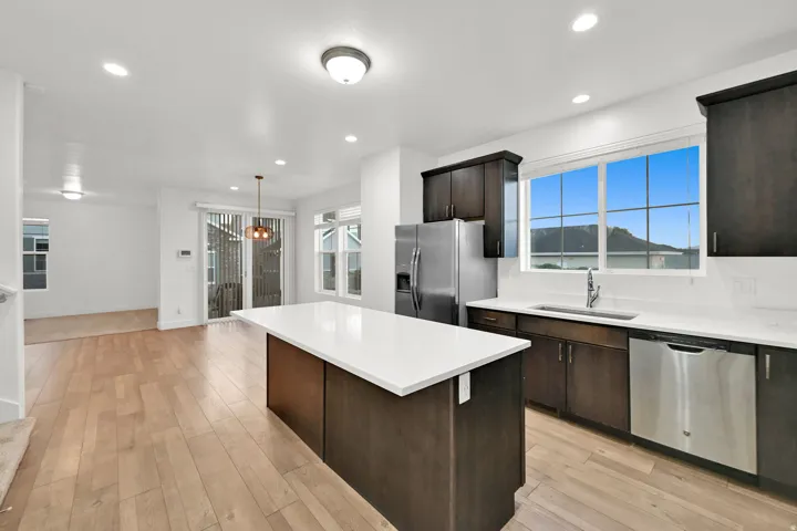 Kitchen featuring dark wood-finish cabinetry, white countertops, a stainless steel refrigerator, and a stainless steel dishwasher