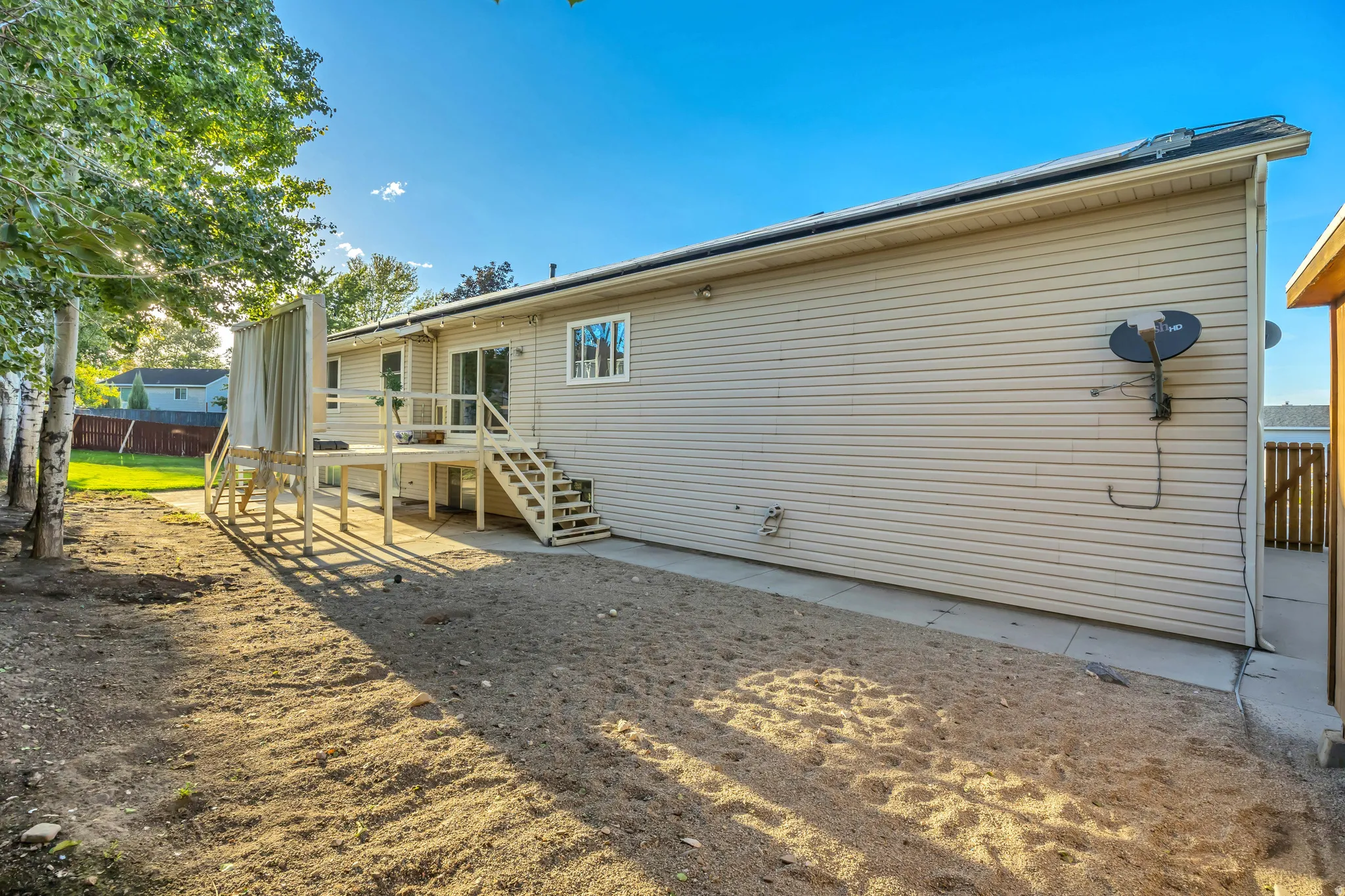 Rear exterior featuring neutral-toned siding, a multi-level wood deck, sliding glass door access, and a dedicated concrete pathway