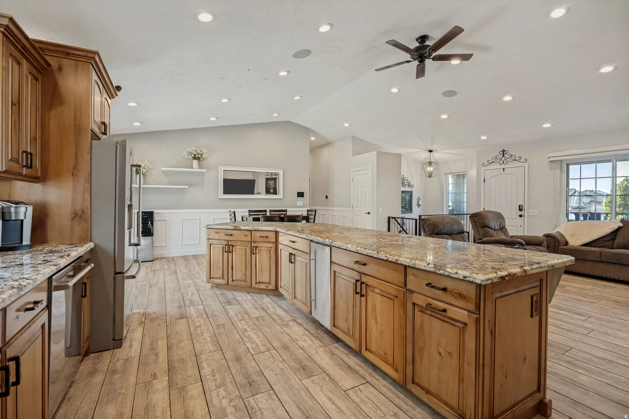 Open concept kitchen with wood-finish flooring, wood cabinetry, and granite countertops