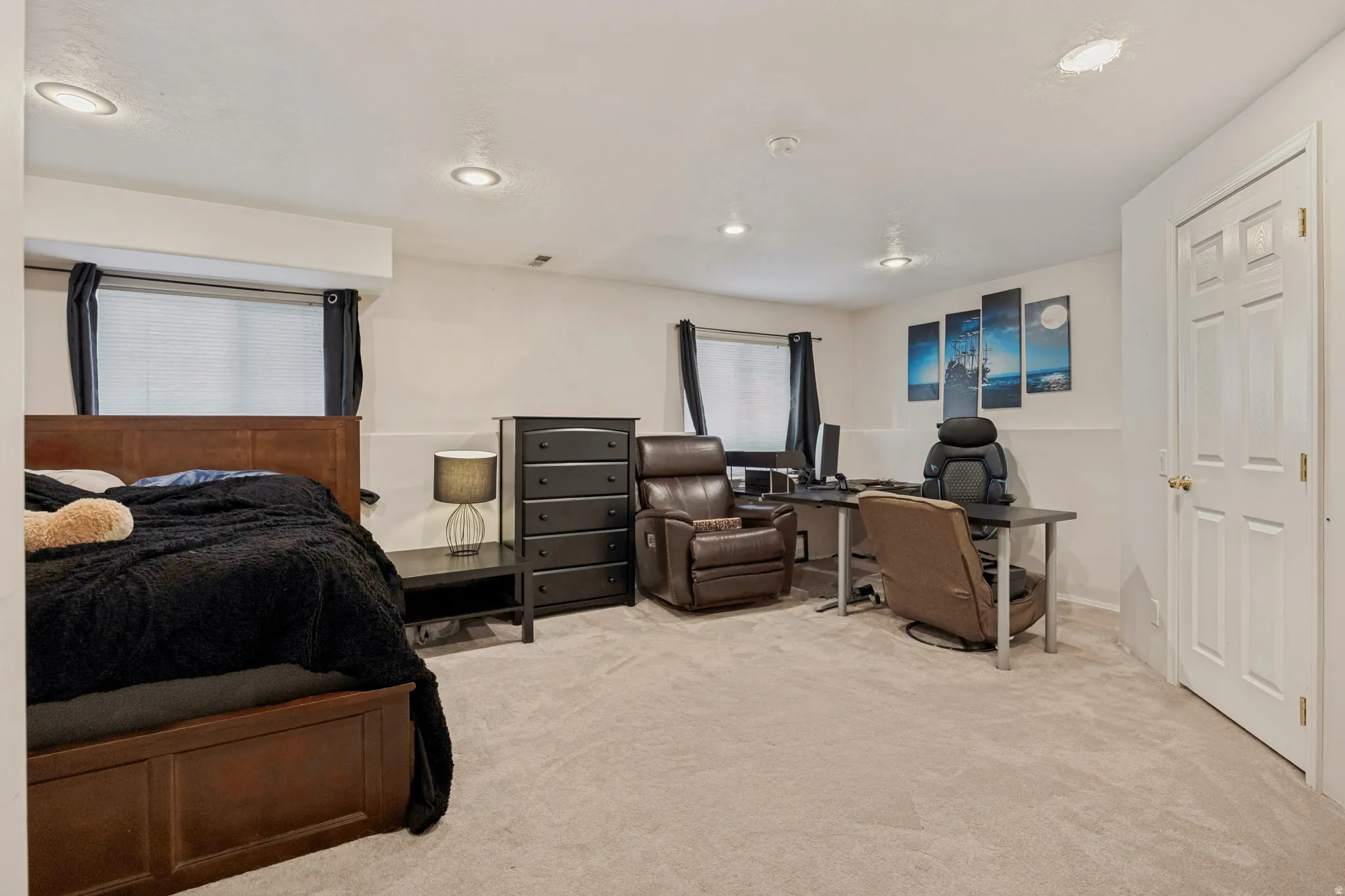 Carpeted flooring complemented by recessed lighting and a white paneled door