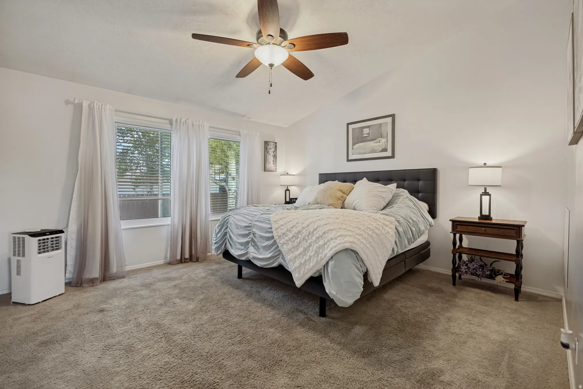Vaulted ceiling with a wood-finish ceiling fan, wall-to-wall carpeting, and two windows