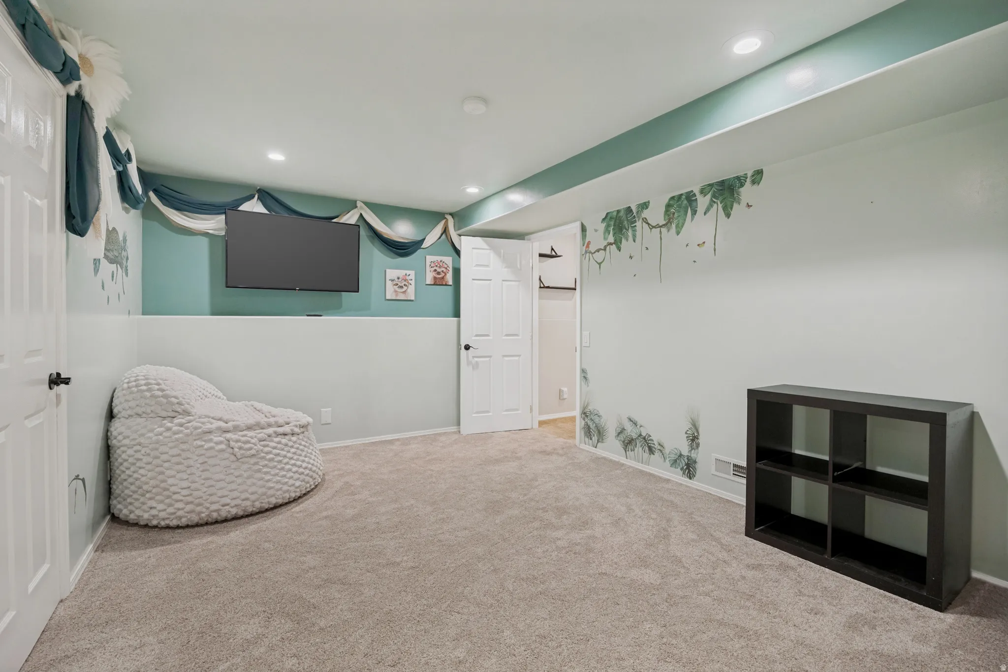 Carpeted room featuring recessed lighting, a built-in wall-mounted television, and a neutral color palette