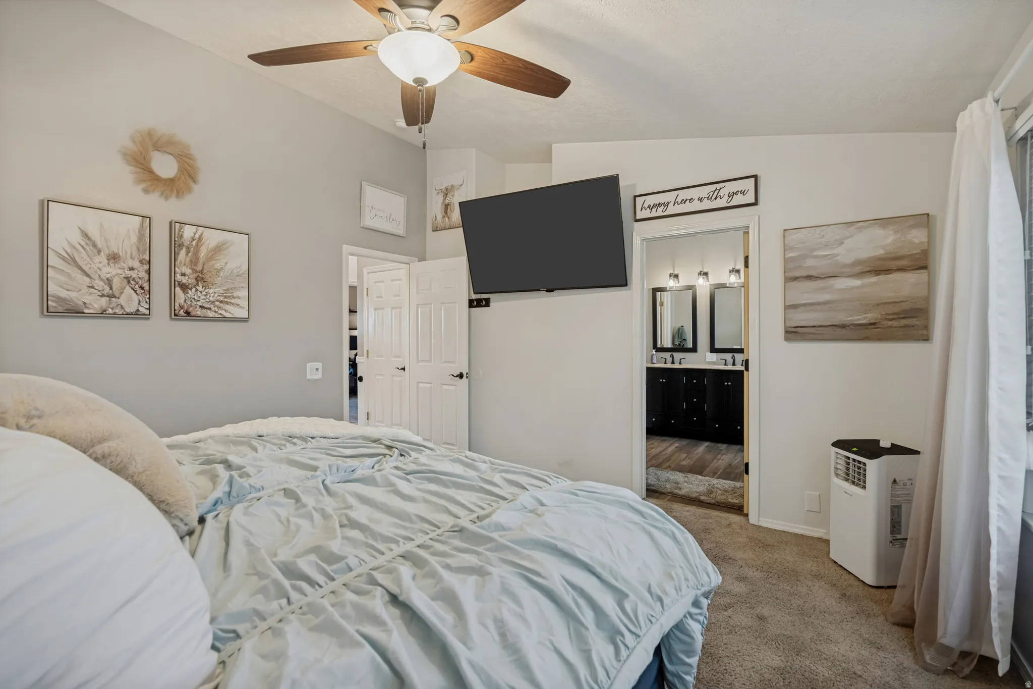 Carpeted room with a ceiling fan, light gray painted walls, and a window with white curtains