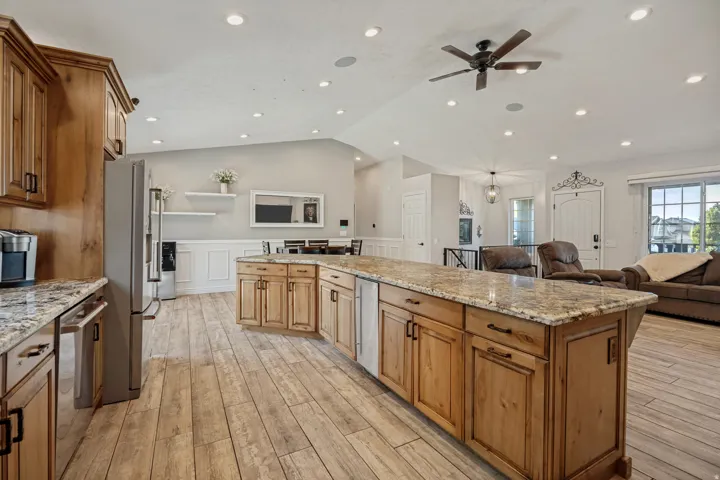 Open concept kitchen with wood-finish flooring, wood cabinetry, and granite countertops