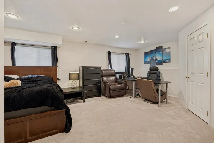 Carpeted flooring complemented by recessed lighting and a white paneled door