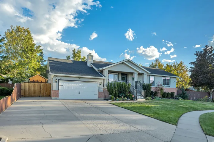 Light-colored exterior siding with brick accents, attached two-car garage, mature landscaping, concrete driveway, and a front walkway