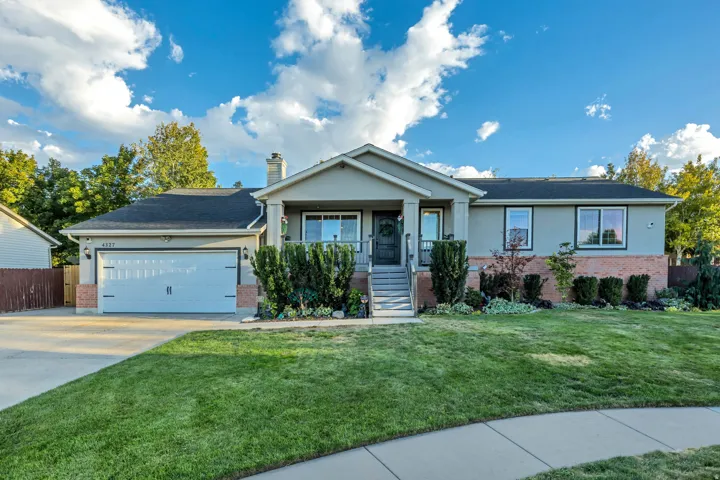 Single-family residence featuring a two-car garage, front porch, and mature landscaping