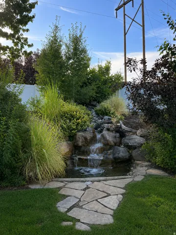 Water feature with natural stone, flagstone pathway, and surrounding landscaping