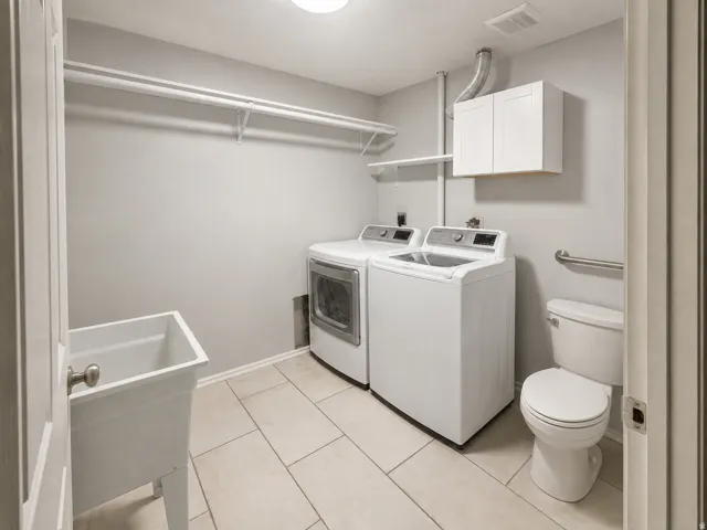 Laundry room featuring light-toned tile flooring, a utility sink, and wall-mounted shelving