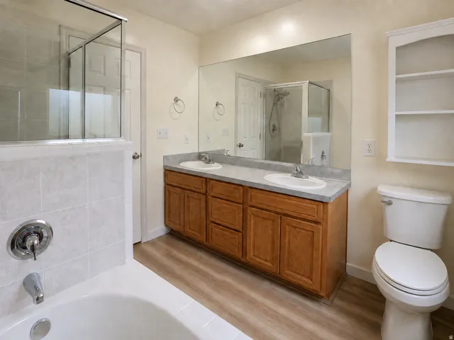 Double vanity with integrated sinks, wood-finish cabinetry, and a large wall-mounted mirror
