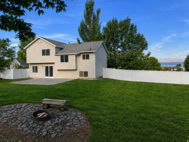 Expansive green lawn, white privacy fencing, paved patio, and a fire pit area