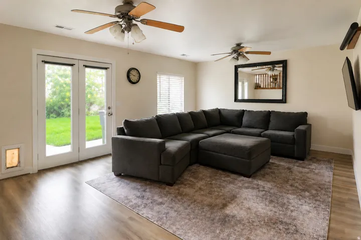 Bright living space with wood-finish flooring, white walls, and dual ceiling fans