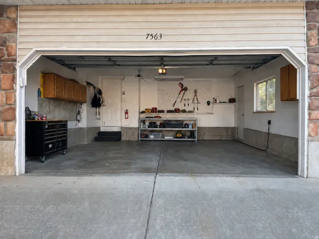 Attached garage featuring a concrete floor, built-in cabinetry, and a window