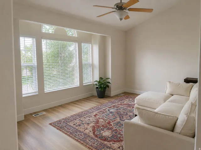 Vaulted ceiling with a ceiling fan, wood-finish flooring, and multiple windows with blinds