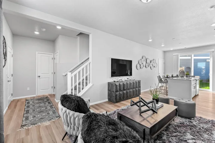 Open-concept living area featuring wood-finish flooring, recessed lighting, and a white staircase with wood railings